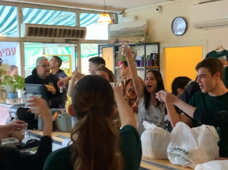חגיגה בחומוס הבוטקה, אנשים שמחים מברכים עם חומוס ופול, אווירה נעימה בחומוסיה בצפון.